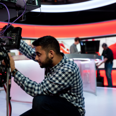 A male in a TV studio working on a camera