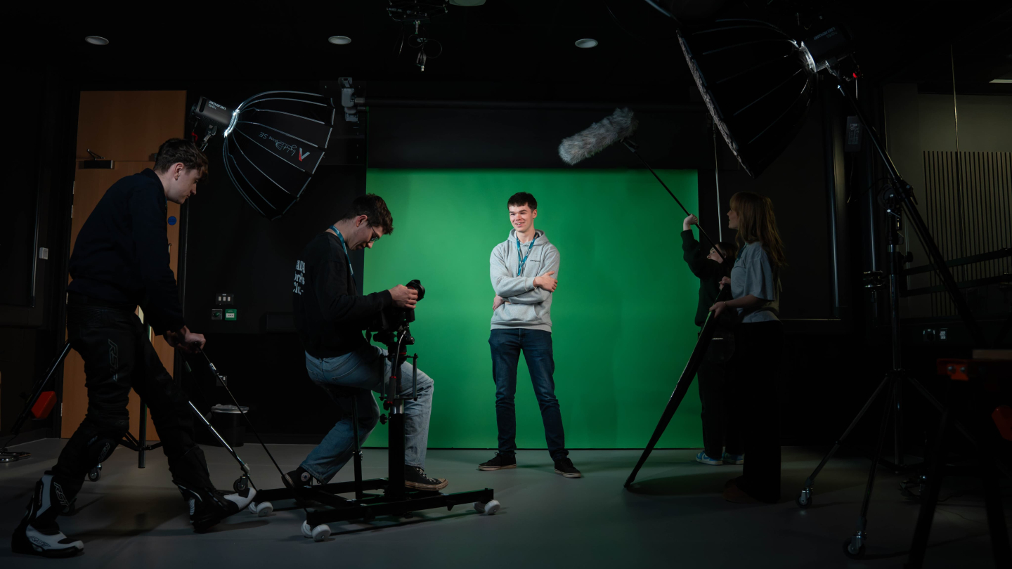 A group of people working in a studio setting with a green screen backdrop.