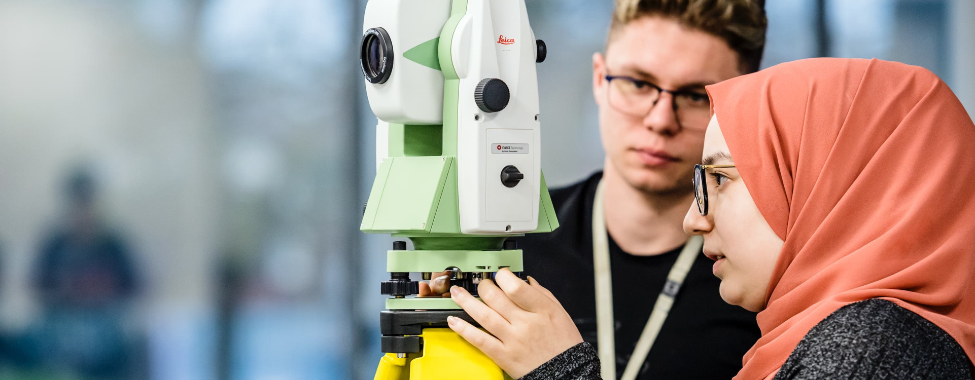 Two people working with a surveying instrument.