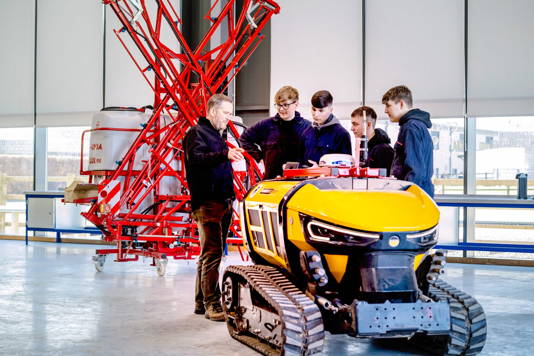 A group of students gather round a vehicle while a teacher talks