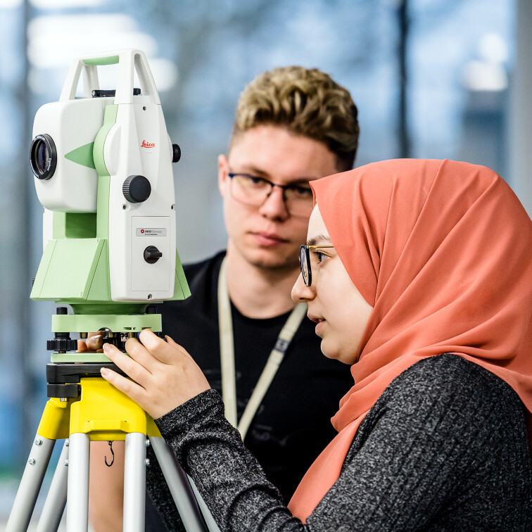 A male and female student using an automatic level